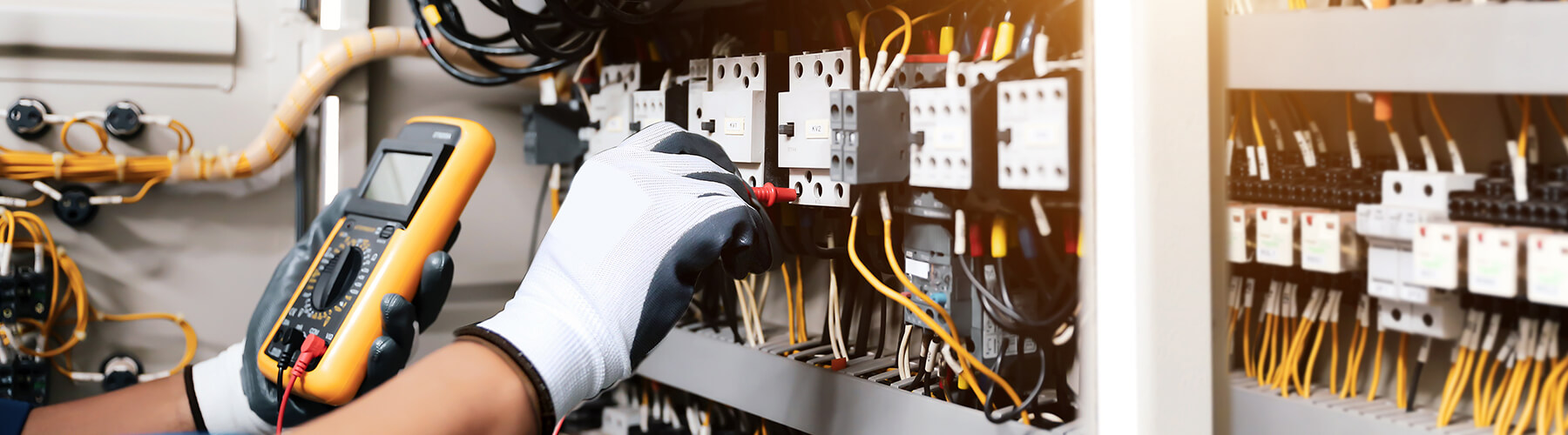 Person arbeitet an verschiedenen Kabelleitungen an einem Schaltschrank